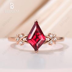 a ring with a red stone and white stones on it, sitting on top of a table