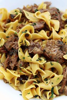 a white plate topped with pasta and meat