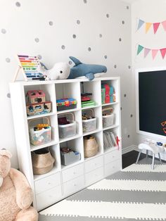 a child's playroom with white bookcases and polka dot wallpaper