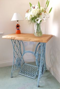 a blue table with flowers on it and a lamp in the corner next to it