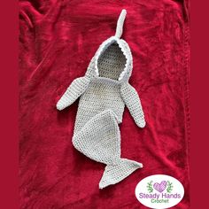 a crocheted baby's bodysuit is laying on top of a red blanket