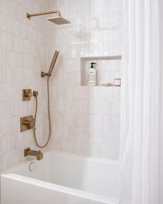 a bath tub with a shower head and hand held faucet