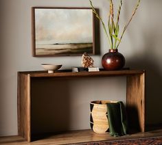 a table with vases and other items on it in front of a framed painting