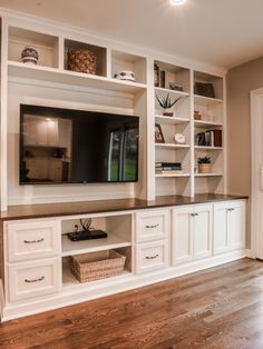 a large entertainment center with white cabinets and wood floors