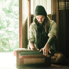 a man sitting on the floor next to an old suitcase with his hands in it