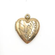 "Vintage Gold Heart Shaped Engraved Photo Locket. The locket is a lovely vintage 12K gold filled over sterling silver heart shaped locket. It has an engraved design on the front of a heart and flower. It snaps shut and contains two frames inside for your photos. The locket is marked 12K on STERLING. This piece is on good vintage condition with slight darkening on the bail where it meets the heart.   15/16\" l x 3/4\" w 3/8\" projection 3 grams Good vintage condition" Heirloom Engraved Locket Necklace For Valentine's Day, Vintage Etched Heart Pendant Jewelry, Valentine's Day Vintage Etched Jewelry, Antique Etched Heart Jewelry, Antique Etched Heart-shaped Jewelry, Engraved Heart-shaped Brass Jewelry, Vintage Personalized Open Heart Jewelry, Vintage Double Heart Engraved Locket Necklace, Vintage Locket Necklace With Hallmark For Memorial