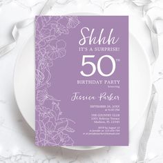 a purple and white birthday party card with flowers on it, sitting on top of a plate