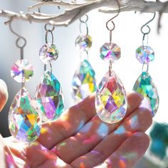 a person is holding some colorful earrings in their hand with the sun shining on them