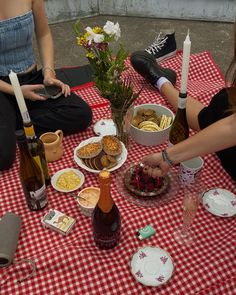 two women sitting at a picnic table with food and drinks