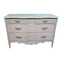 an antique dresser with white paint and green trimmings on the top, against a white background