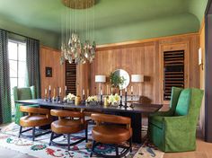 an elegant dining room with green chairs and chandelier hanging from the ceiling, surrounded by wood paneling