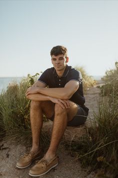 a man is sitting on the beach with his legs crossed and looking at the camera