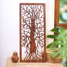 a wooden sculpture with a tree on it next to a potted plant