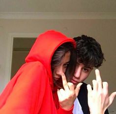 a man and woman dressed in red posing for the camera with their hands up to sign peace