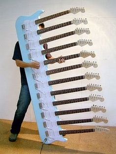 a man standing next to a giant guitar rack