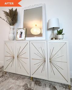 a white sideboard with gold accents and a mirror on top, next to a lamp