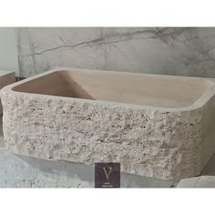 a stone bathtub sitting on top of a white counter next to a marble wall