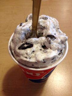 an ice cream sundae with oreo cookies on top is shown in a paper cup