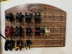 a wooden rack with many different types of fishing reels hanging from it's sides