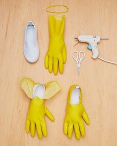 several pairs of yellow gloves are on a wooden table with scissors and glue, one is being used as a hairdryer