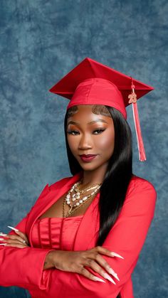 a woman wearing a red graduation cap and gown with her arms crossed in front of her chest