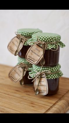 three jars filled with jam sitting on top of a wooden cutting board