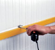 a person using a power drill to attach a yellow strip on the side of a building