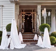 halloween decorations with ghost heads and white cloths on the front steps of a house