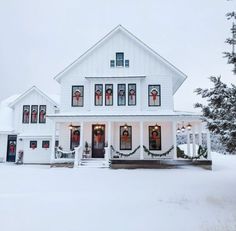 a large white house with christmas decorations on the front door and windows covered in snow