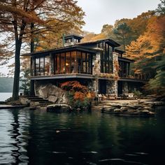 a large house sitting on top of a lake surrounded by trees and rocks in the fall