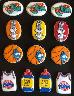 decorated cookies in the shape of bugs and basketballs are on a black tray with white frosting