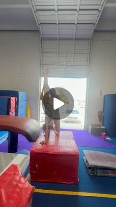 a person standing on top of a red object in a room with blue and yellow flooring