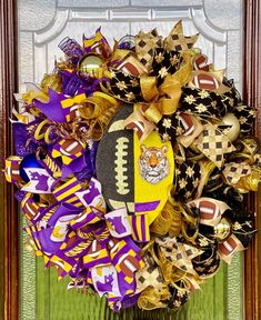 a football wreath with purple, yellow and gold decorations on it in front of a door