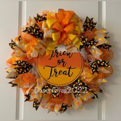 an orange and black wreath with the words trick or treat on it