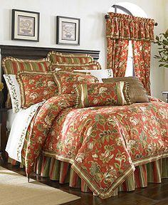 a bed in a bedroom with red and gold comforter set on top of it