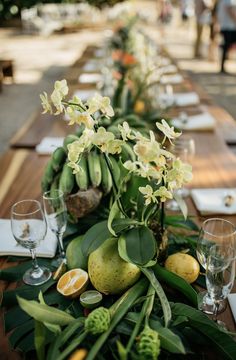 a long table is set with fruit and flowers for an outdoor dinner or party event