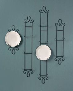 three plates are hanging on the wall next to each other with decorative ironwork around them