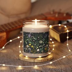 a candle sitting on top of a wooden table next to a string of lights and a guitar