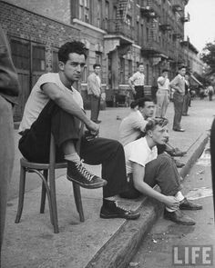 black and white photograph of men sitting on the curb