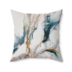 a white and blue pillow with an abstract design on the front, along with gold accents