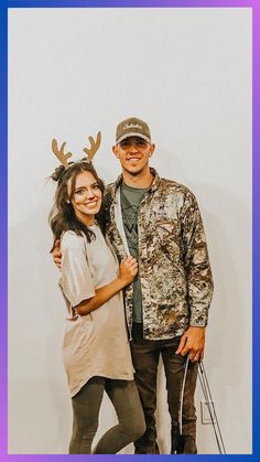 a man and woman standing next to each other in front of a wall with deer antlers on it