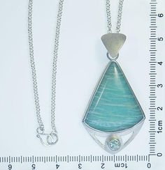 Description Materials Additional Info This one-of-a-kind necklace features a captivating natural teal amazonite mined in East Haddam, Connecticut, paired with a gentle aqua-teal tourmaline gemstone from Maine. I created the entire pendant using recycled Argentium sterling silver (which is tarnish-resistant), and recycled sterling silver for the tourmaline setting. The silver in the pendant all has a lovely matte finish, which plays beautifully off of the sparkle of the tourmaline.The removable 1 Turquoise Aquamarine Gemstone Necklace, Unique Silver Amazonite Jewelry, Handmade Aquamarine Pendant Necklace, Silver Amazonite Necklace With Natural Stones, Amazonite Gemstone Pendant Jewelry, Handmade Silver Amazonite Necklace, Larimar Gemstone Pendant Necklaces, Larimar Gemstone Pendant Necklace, Silver Amazonite Gemstone Jewelry