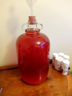 a large red jug sitting on top of a wooden table next to some white containers