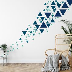 a wall with blue triangles on it next to a chair and potted plant