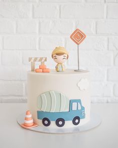 a white cake with a blue truck on it and a traffic sign in the background