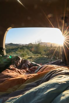 the sun shines brightly through the window of a camper's bed in an open field