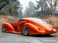 an orange car parked on the side of a road next to tall grass and trees