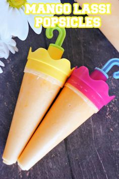 there are two ice cream cones with umbrellas in them on the table next to flowers