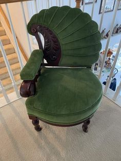 a green chair sitting on top of a carpeted floor next to a stair case