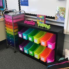 a classroom desk with lots of colorful bins on the top and bottom drawers in front of it